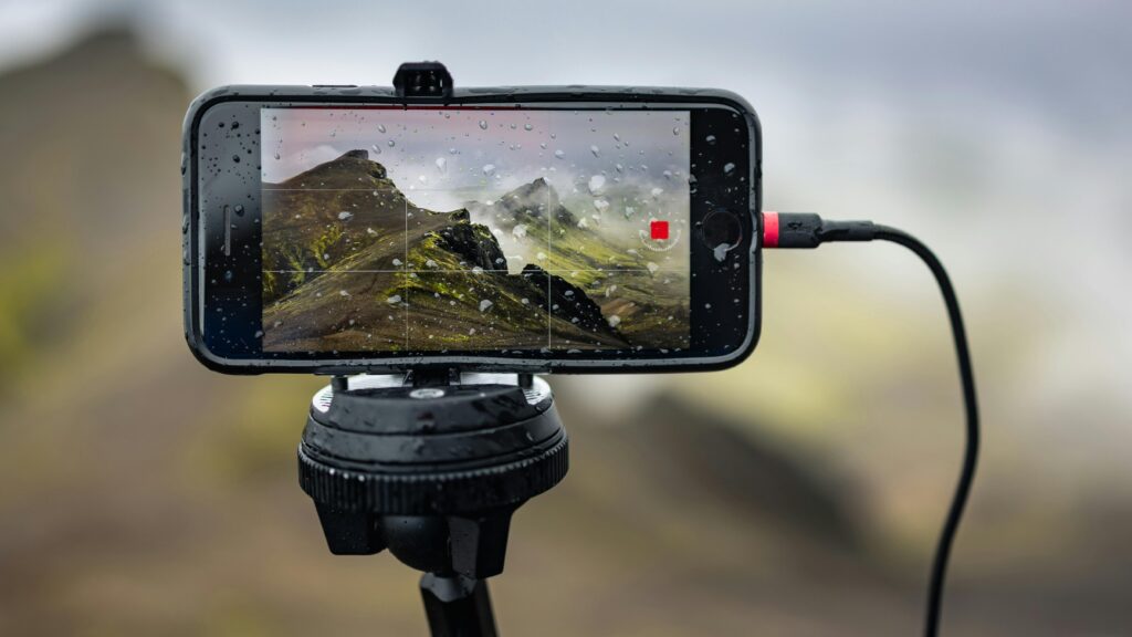 A mobile on a tripod recording video in the outdoors.