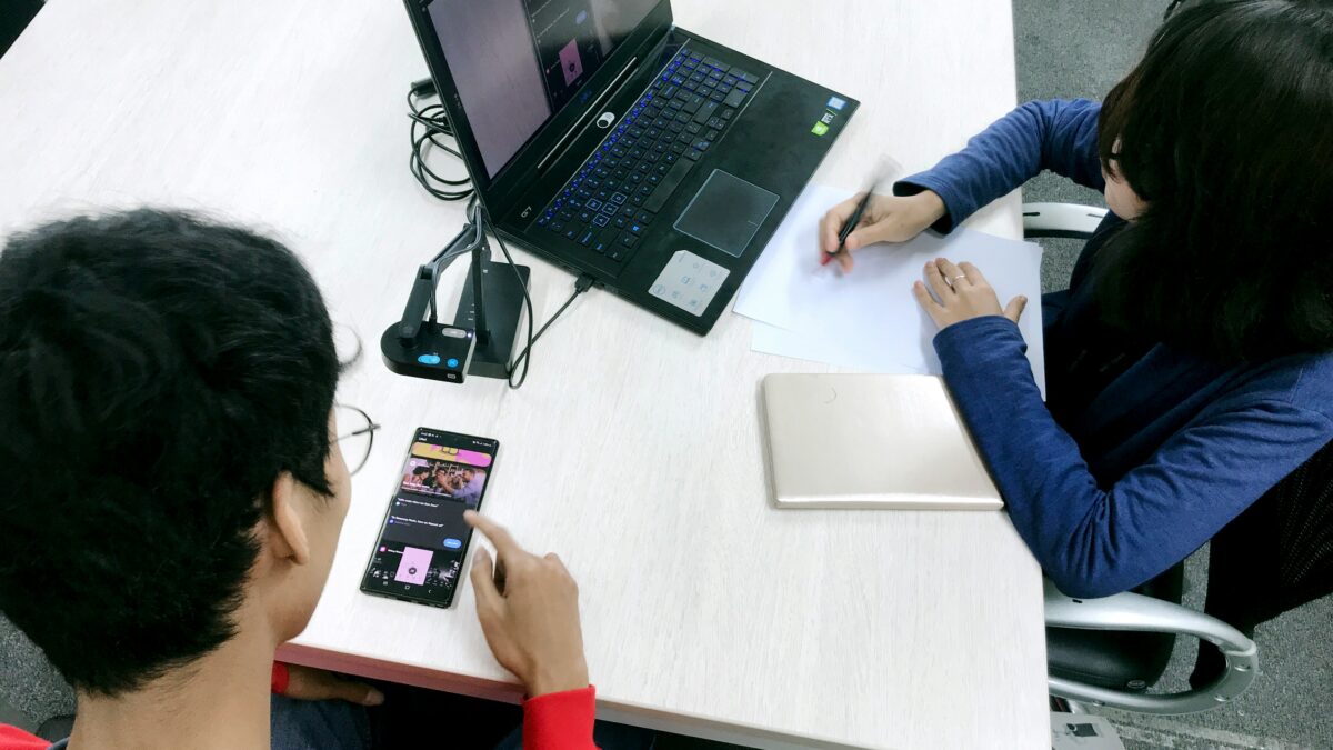 Two person doing A/B testing. One person is using laptop and the other person is using mobile.