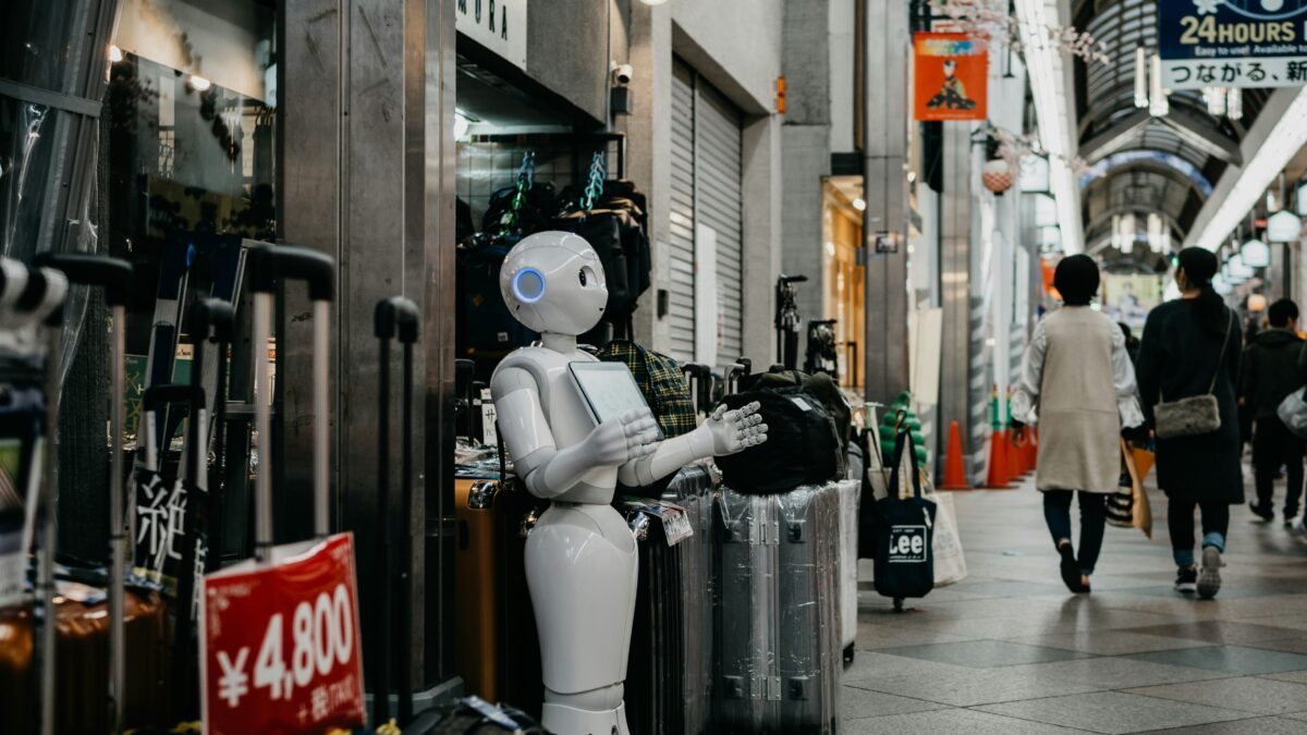 A bot is standing outside a shop holding a board.