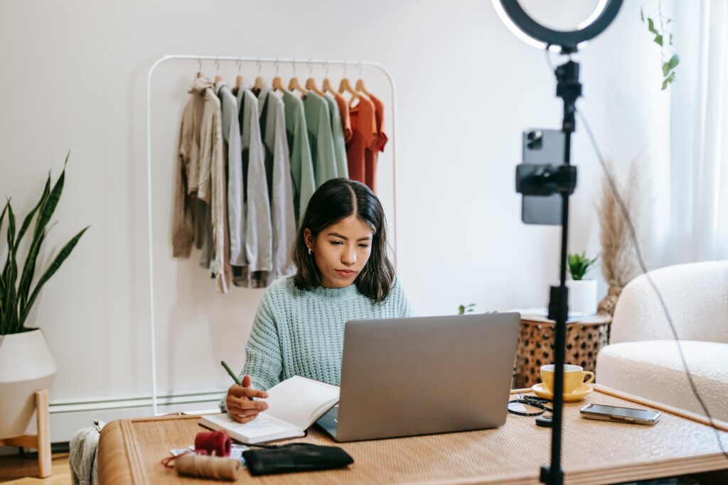 A girl influencer with a laptop, pen, and notebook.