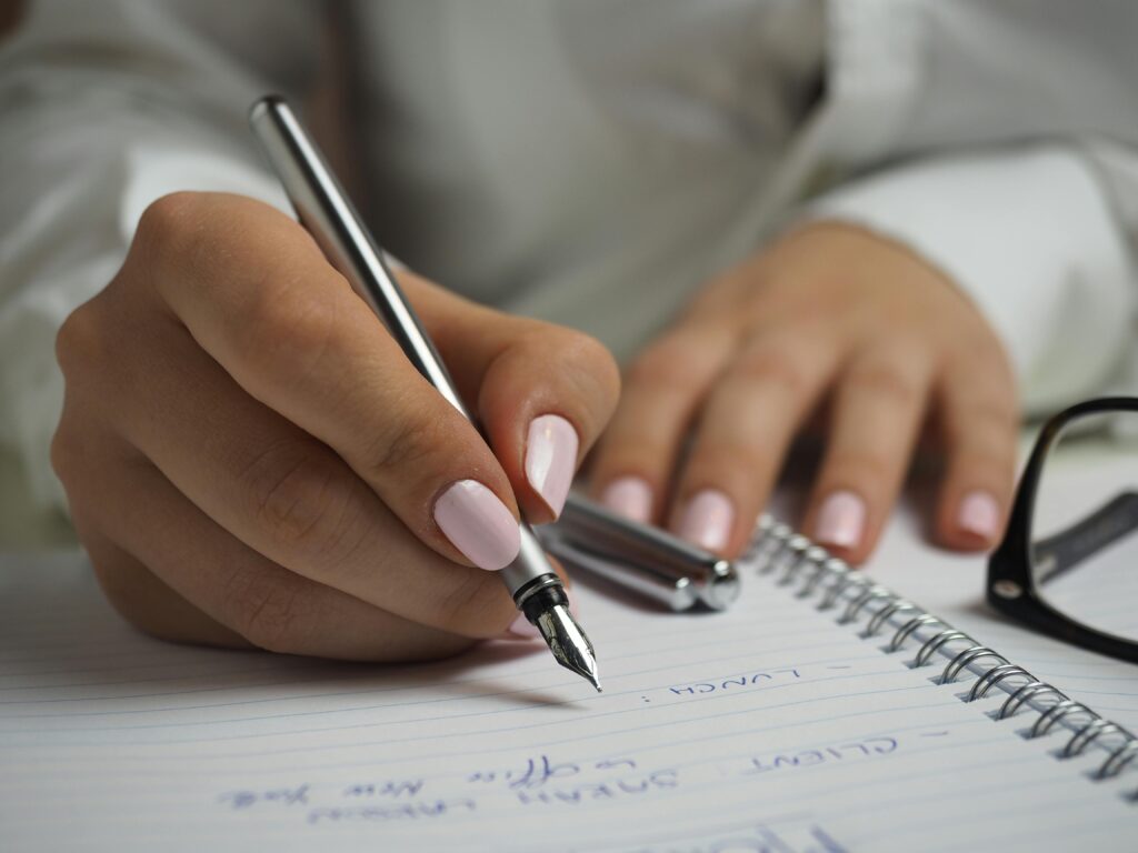 A person is writing content in a notebook.