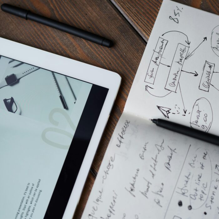 A tab displaying some text related to content writing placed next to a journal and a pencil