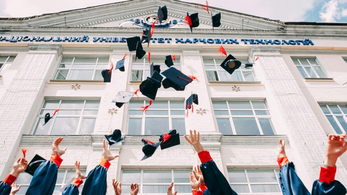 Group of fresh graduates throwing their academic hats in the air