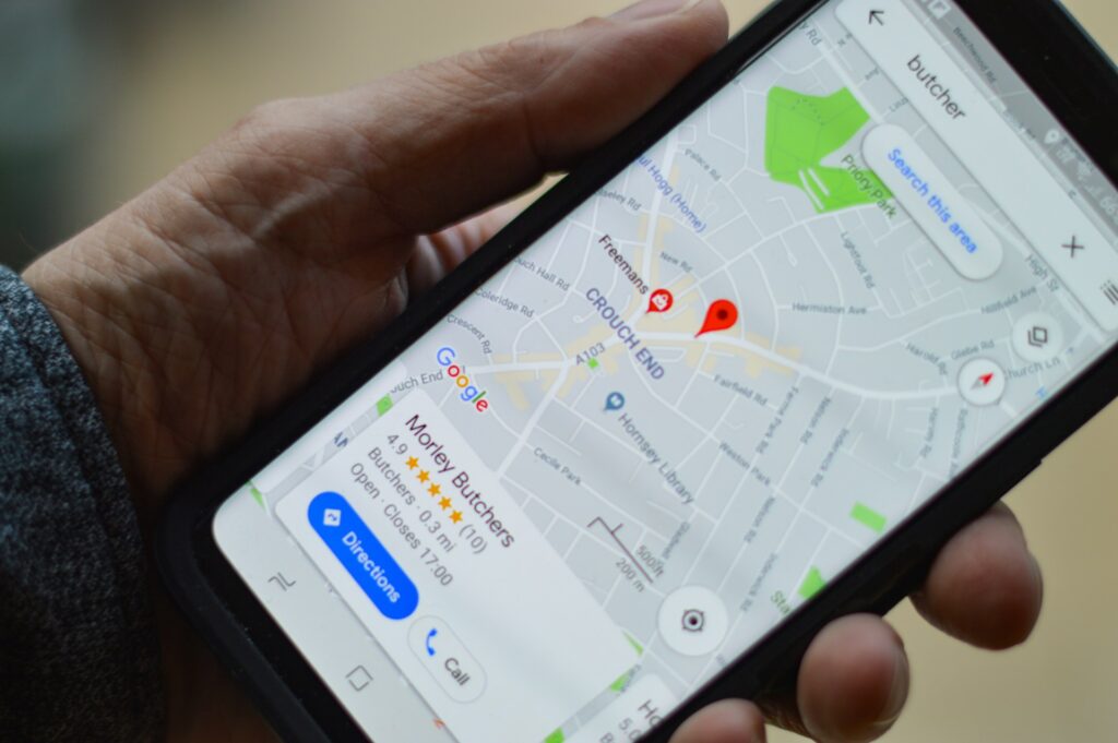 A hand holding a smartphone showing a map on the screen with a red location pin labeled